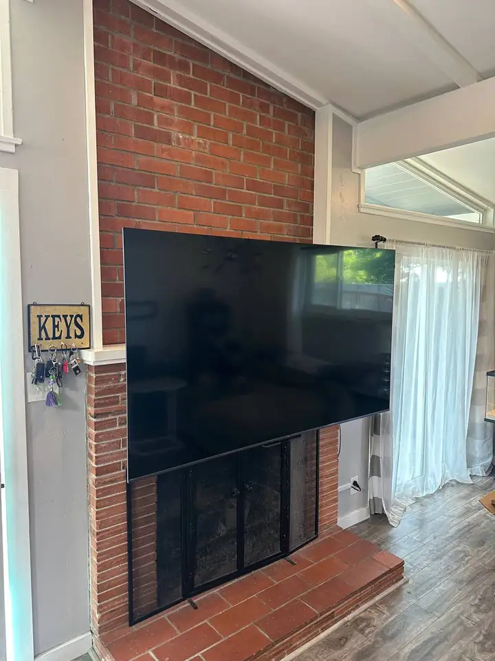 TV on a MantelMount pulled down in front of a brick fireplace