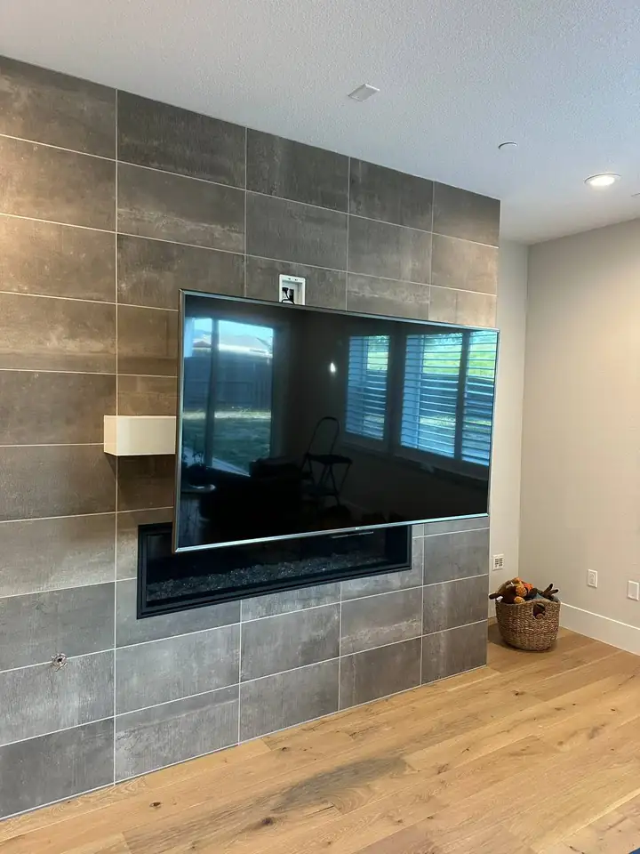 TV on a MantelMount pulled down in front of a tiled fireplace